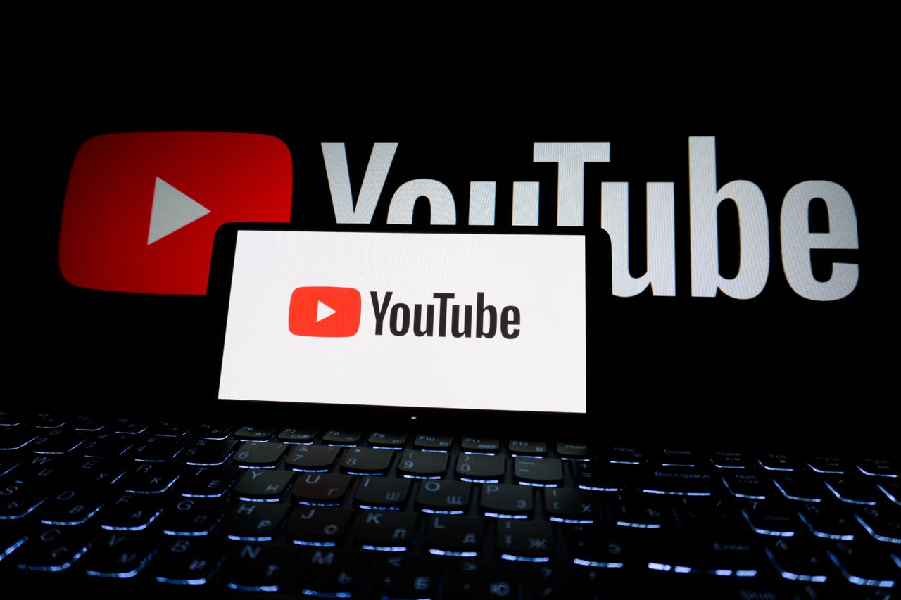 Vue rapprochée du logo YouTube affiché sur l’écran d’un ordinateur portable dans un environnement sombre.